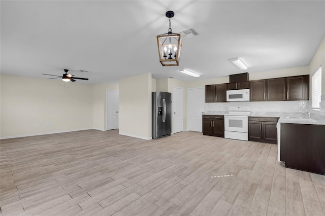 kitchen with dark brown cabinetry, hanging light fixtures, light hardwood / wood-style flooring, white appliances, and decorative backsplash