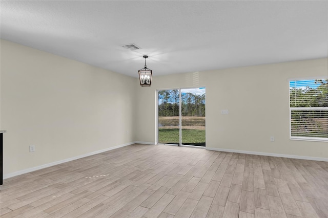 empty room featuring an inviting chandelier and light wood-type flooring