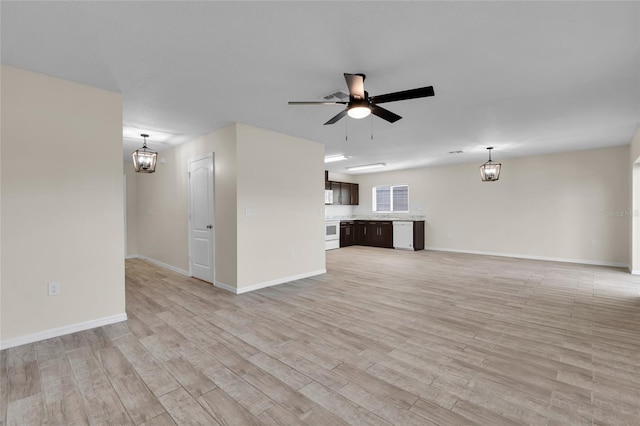 unfurnished living room with ceiling fan with notable chandelier and light wood-type flooring