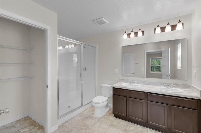 bathroom featuring vanity, a textured ceiling, a shower with door, and toilet