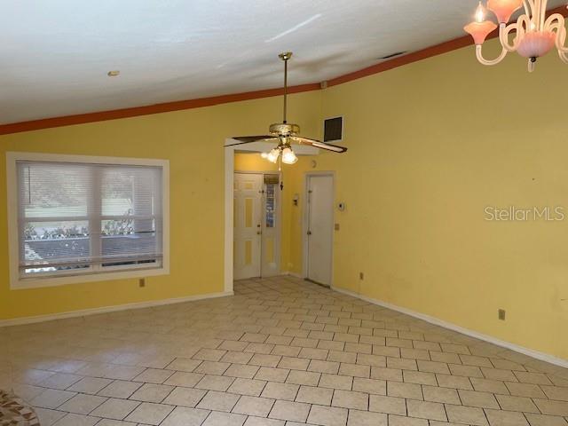 spare room featuring ceiling fan with notable chandelier, vaulted ceiling, and ornamental molding