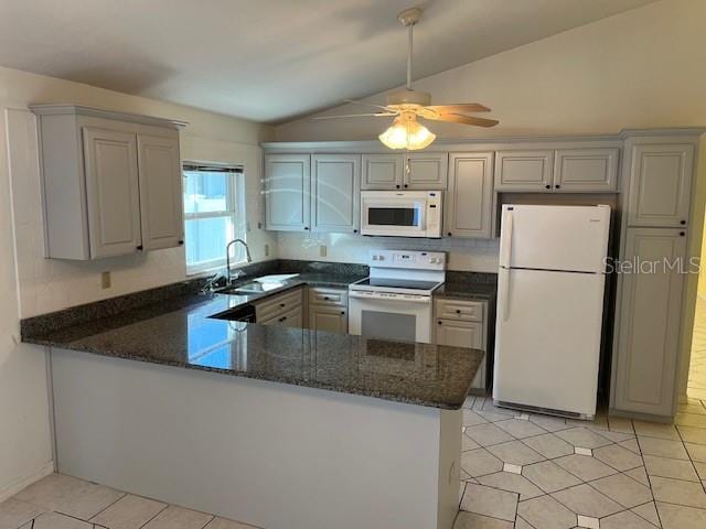 kitchen featuring kitchen peninsula, lofted ceiling, sink, and white appliances