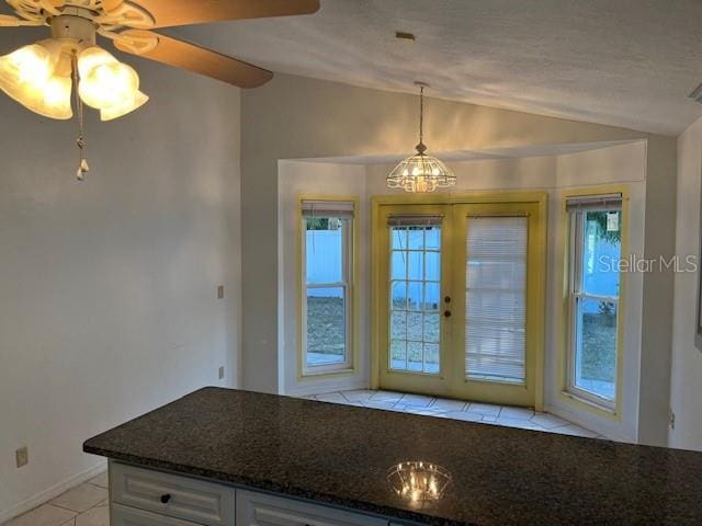 kitchen with pendant lighting, dark stone countertops, white cabinetry, and vaulted ceiling