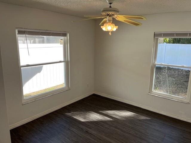 empty room featuring ceiling fan, dark wood-type flooring, and a textured ceiling