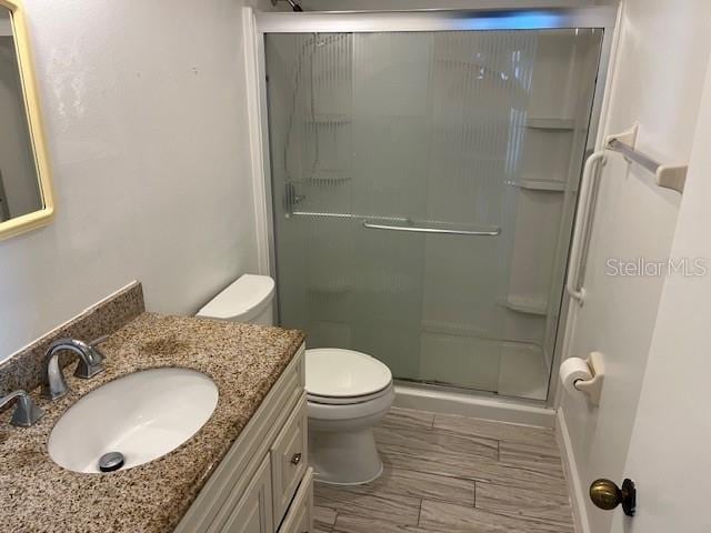 bathroom featuring vanity, toilet, and a shower with door