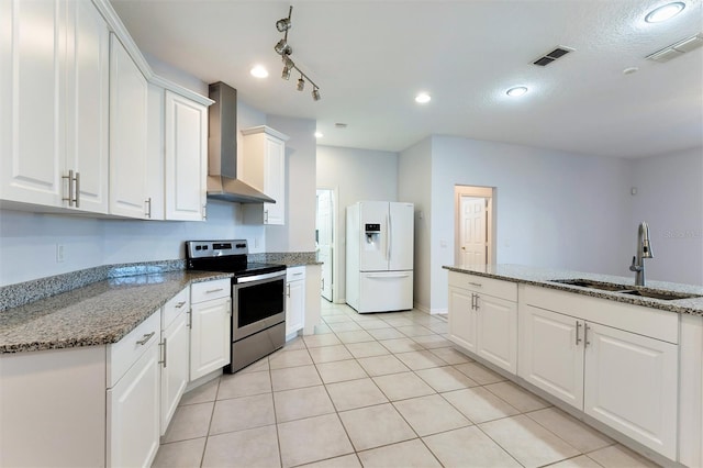 kitchen with sink, wall chimney range hood, white refrigerator with ice dispenser, electric stove, and white cabinets