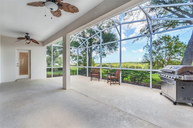 view of patio featuring a grill, ceiling fan, and glass enclosure