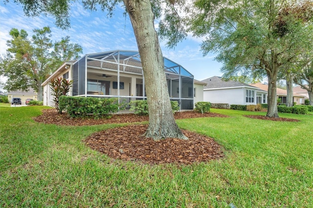 back of property with a lanai, ceiling fan, and a lawn