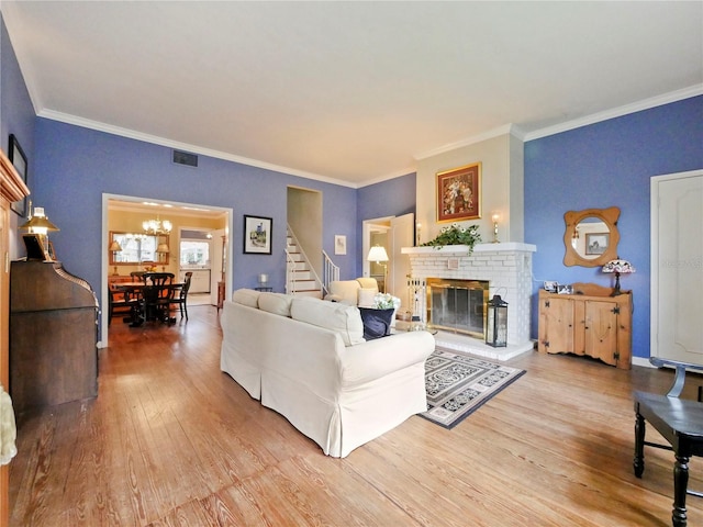 living room featuring a chandelier, a fireplace, wood-type flooring, and ornamental molding