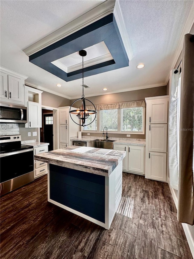 kitchen featuring white cabinets, appliances with stainless steel finishes, pendant lighting, and dark wood-type flooring