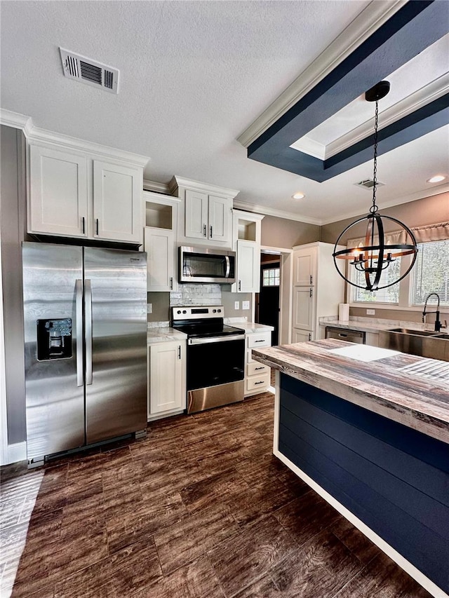 kitchen with stainless steel appliances, dark wood-type flooring, sink, pendant lighting, and white cabinetry