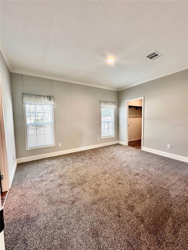 carpeted spare room featuring a textured ceiling, a wealth of natural light, and ornamental molding