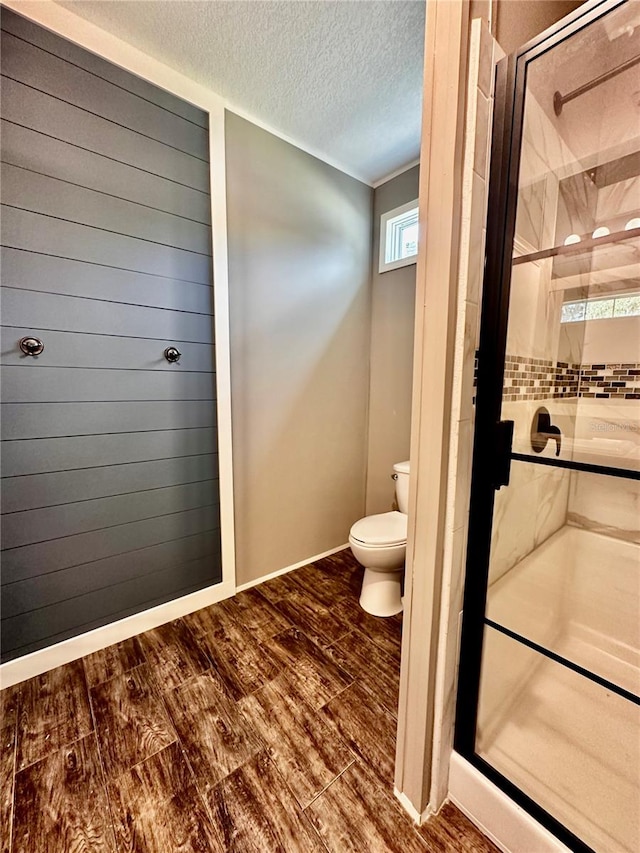 bathroom featuring toilet, an enclosed shower, a textured ceiling, and hardwood / wood-style flooring