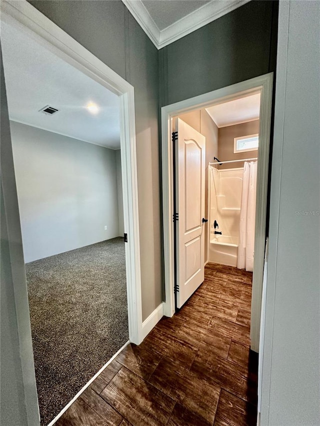 corridor featuring dark carpet and ornamental molding