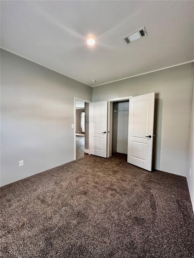 unfurnished bedroom featuring dark colored carpet and a closet