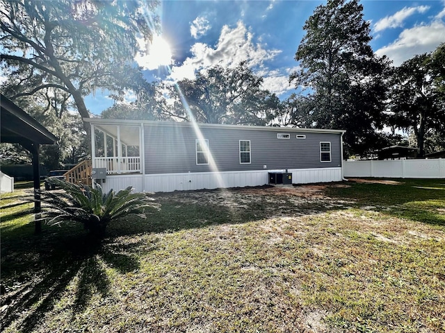 rear view of property featuring central AC unit, a sunroom, and a yard