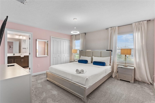 bedroom with connected bathroom, light carpet, a closet, and a textured ceiling