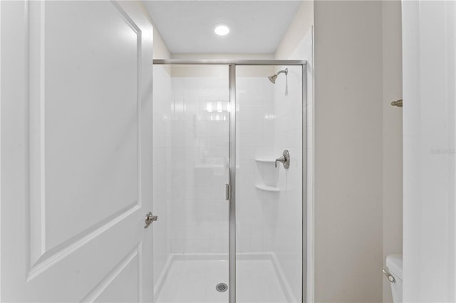 bathroom featuring toilet and a shower with shower door