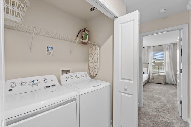 clothes washing area with light carpet and washer and clothes dryer