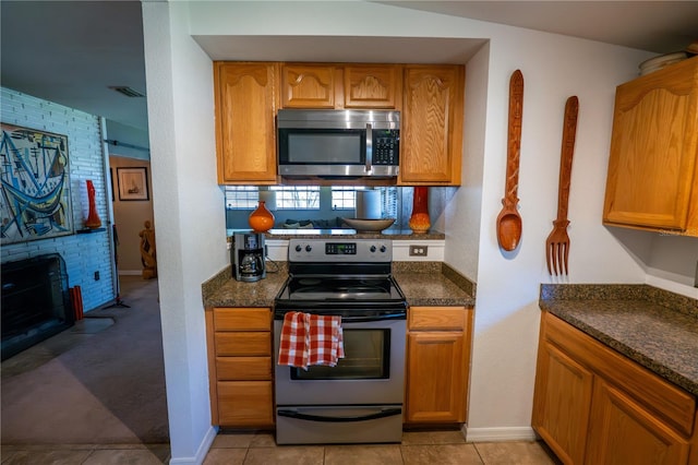 kitchen with light tile patterned floors, stainless steel appliances, and dark stone counters