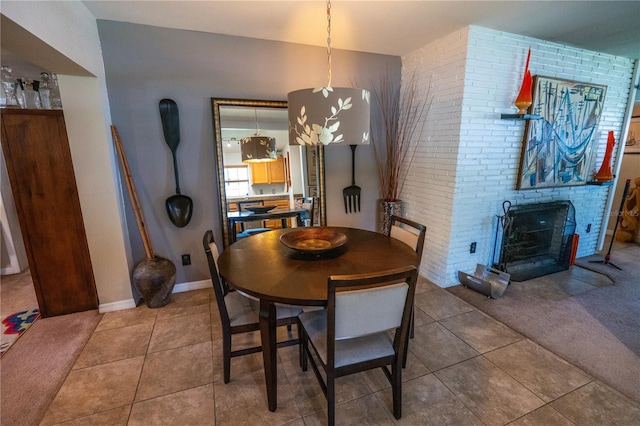 dining room featuring tile patterned flooring, brick wall, and a brick fireplace