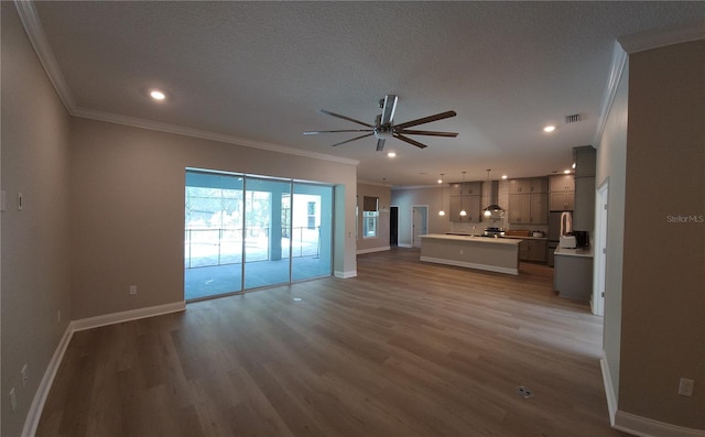 unfurnished living room featuring ceiling fan, ornamental molding, a textured ceiling, and hardwood / wood-style flooring