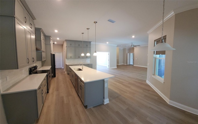 kitchen featuring sink, decorative backsplash, pendant lighting, a kitchen island with sink, and black appliances