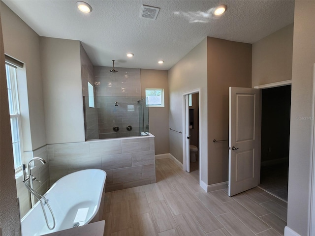 bathroom featuring toilet, a textured ceiling, and plus walk in shower