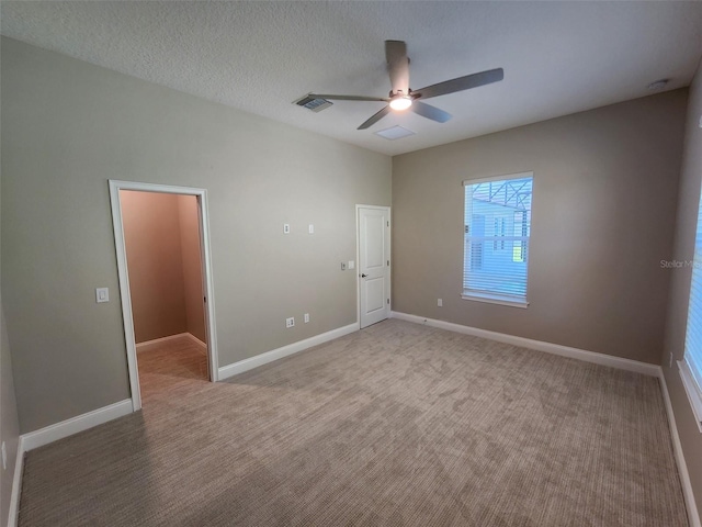 carpeted spare room featuring ceiling fan and a textured ceiling