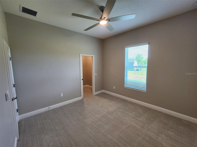 empty room with light carpet, ceiling fan, and a textured ceiling