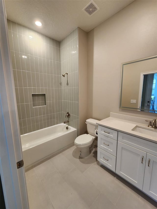 full bathroom with vanity, a textured ceiling, tiled shower / bath combo, tile patterned flooring, and toilet