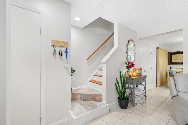 stairway with tile patterned flooring and a textured ceiling