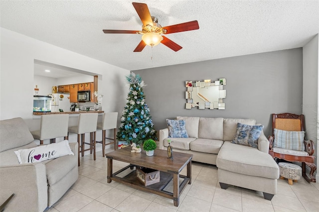 living room featuring ceiling fan, light tile patterned floors, and a textured ceiling