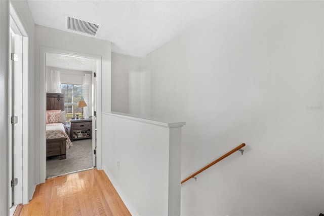 hallway with light hardwood / wood-style floors and a textured ceiling