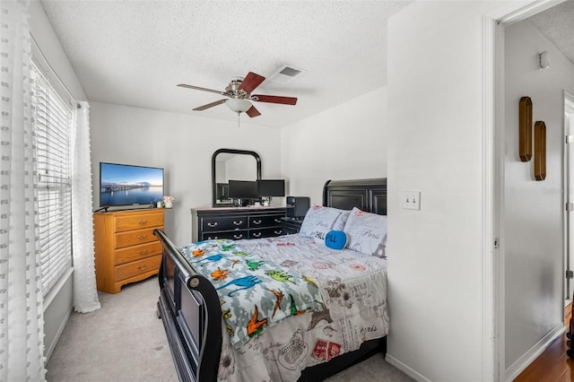 bedroom featuring light carpet, a textured ceiling, and ceiling fan