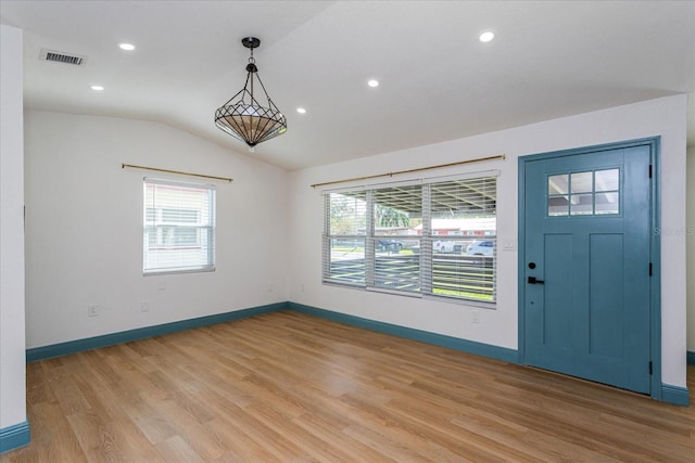 foyer entrance with light hardwood / wood-style floors, vaulted ceiling, and a healthy amount of sunlight