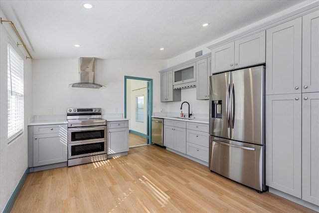 kitchen with gray cabinets, plenty of natural light, wall chimney exhaust hood, and appliances with stainless steel finishes