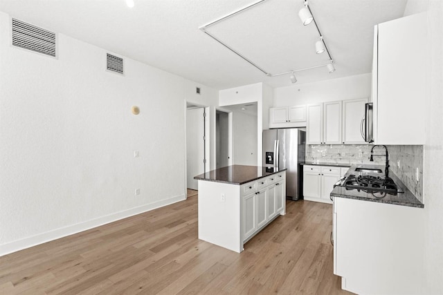 kitchen with white cabinets, light wood-type flooring, a center island, and stainless steel appliances