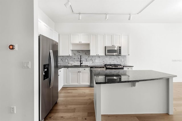 kitchen featuring a center island, sink, appliances with stainless steel finishes, white cabinets, and light wood-type flooring