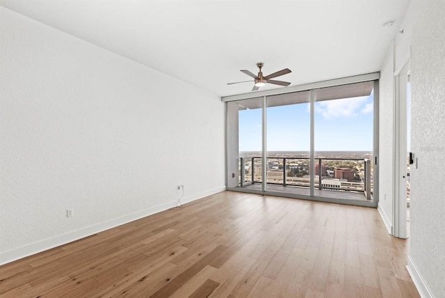 unfurnished room with light wood-type flooring, floor to ceiling windows, and ceiling fan