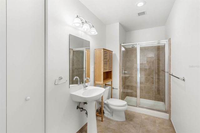 bathroom featuring tile patterned floors, toilet, a shower with shower door, and sink