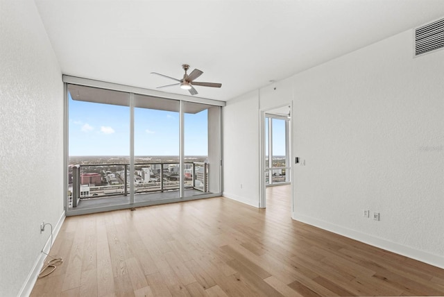 empty room featuring ceiling fan, floor to ceiling windows, and light hardwood / wood-style flooring