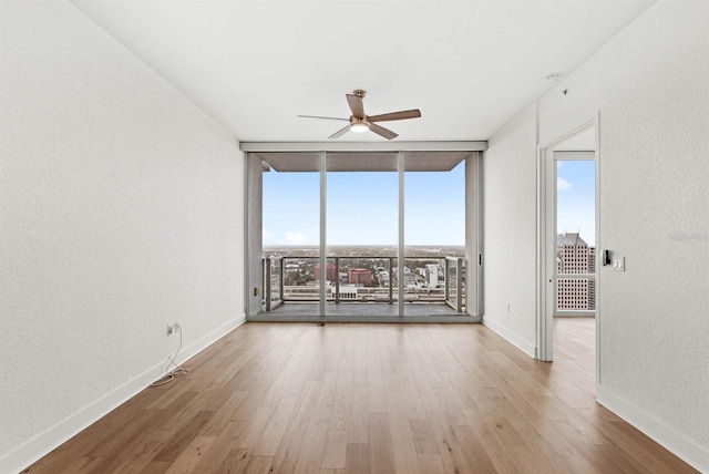 spare room featuring floor to ceiling windows, ceiling fan, and light hardwood / wood-style floors