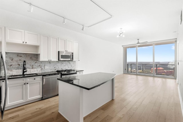 kitchen with white cabinets, sink, rail lighting, appliances with stainless steel finishes, and a kitchen island