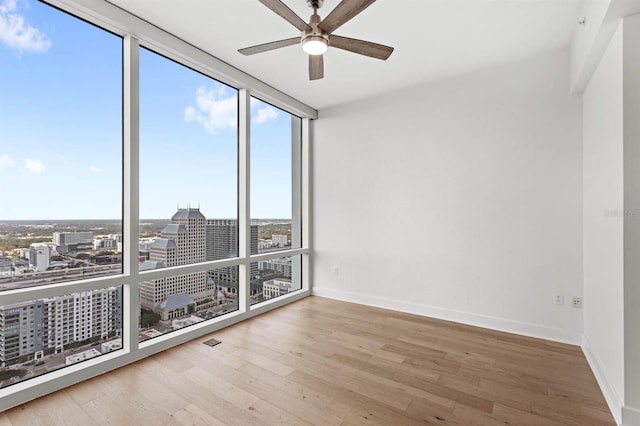 spare room with ceiling fan, floor to ceiling windows, and wood-type flooring