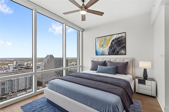 bedroom featuring ceiling fan, hardwood / wood-style floors, and a wall of windows