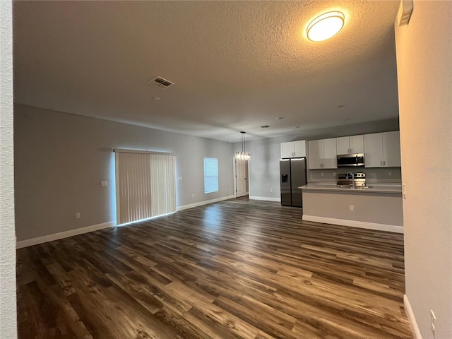 unfurnished living room featuring a textured ceiling, dark hardwood / wood-style floors, and an inviting chandelier