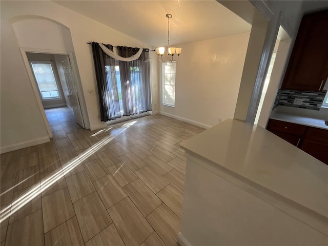 unfurnished dining area featuring a healthy amount of sunlight and a notable chandelier