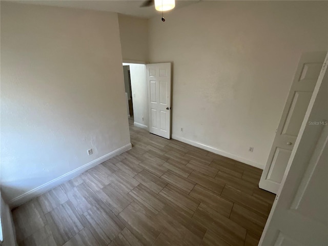 unfurnished room with ceiling fan, a high ceiling, and hardwood / wood-style flooring