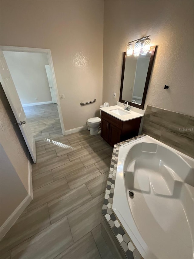 bathroom with tiled bath, vanity, hardwood / wood-style flooring, and toilet